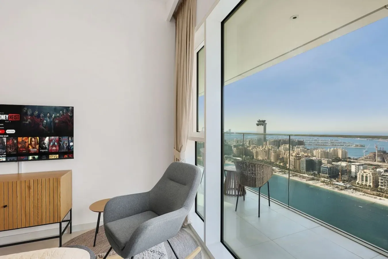 Una sala luminosa se abre a un balcón con vistas a la ciudad y al agua.