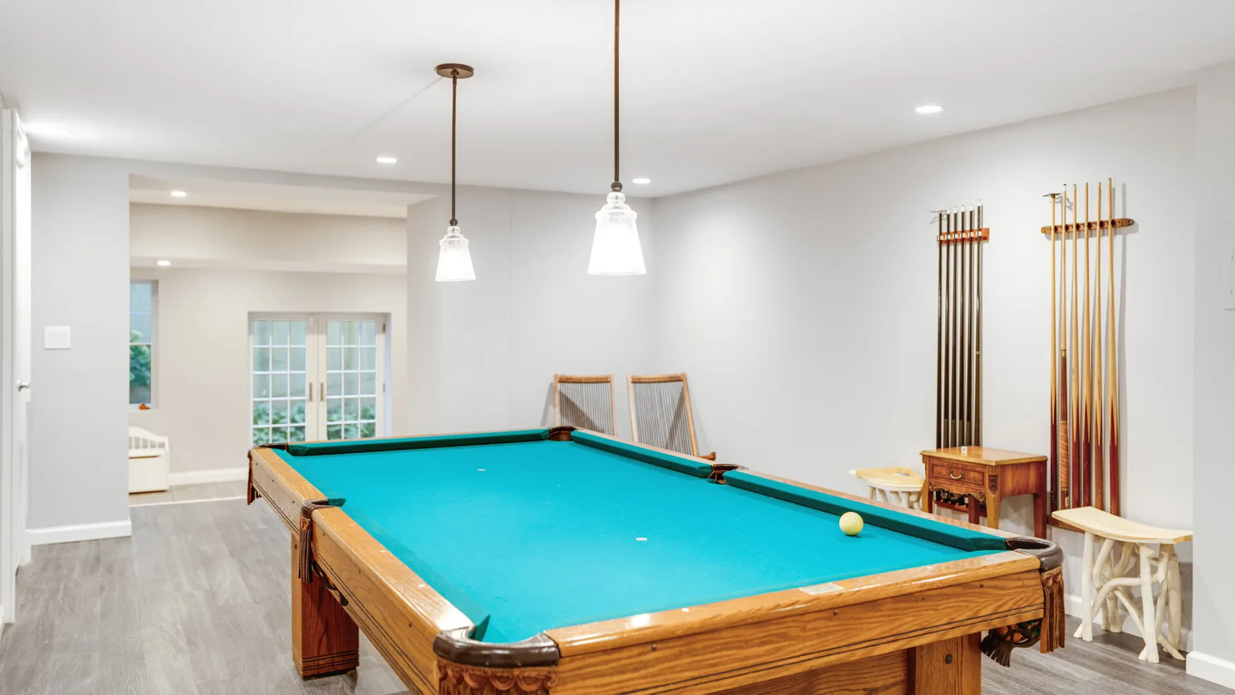 A bright game room features a pool table and cue racks.