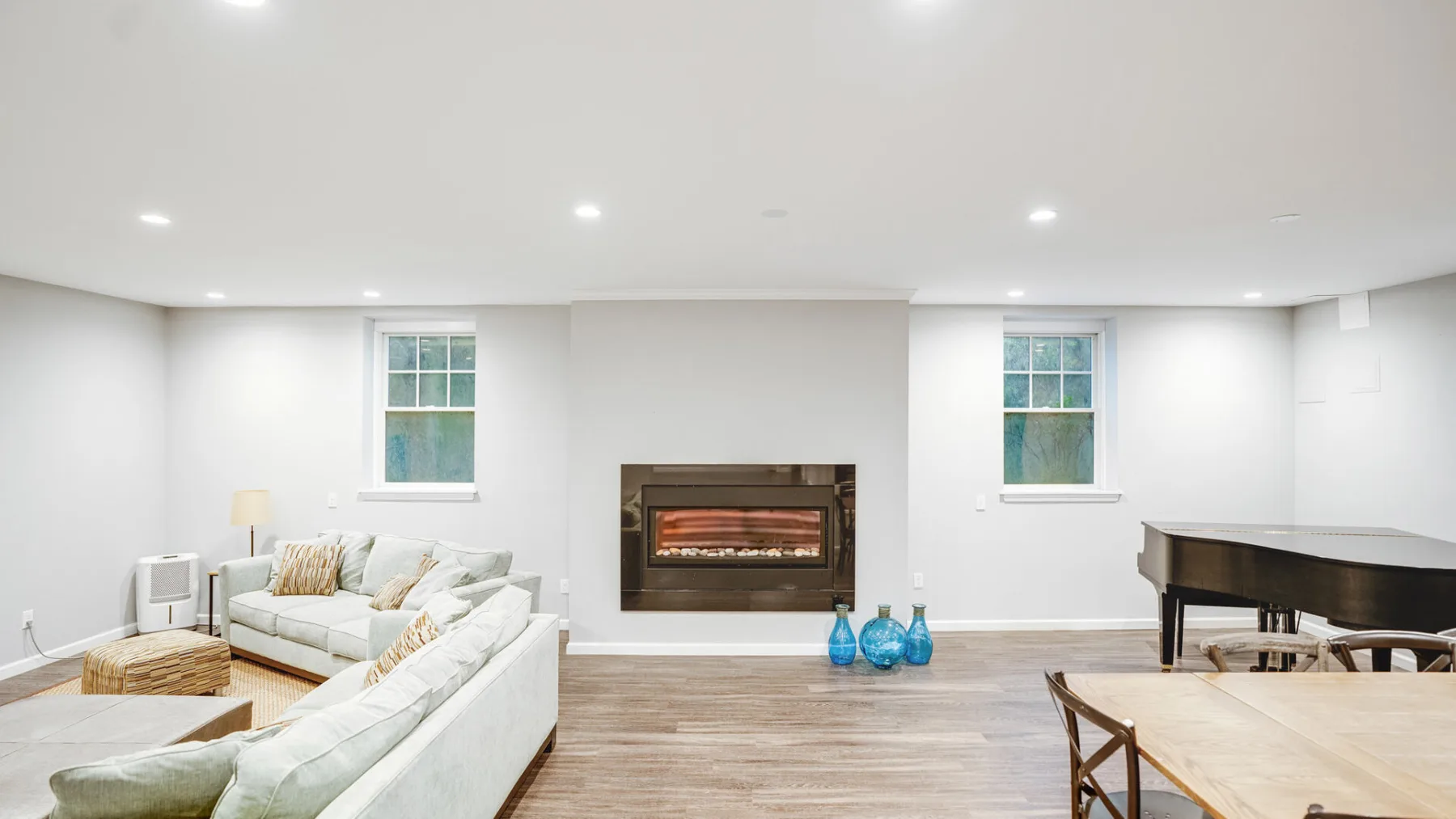 A bright living room with pale seating and a fireplace.