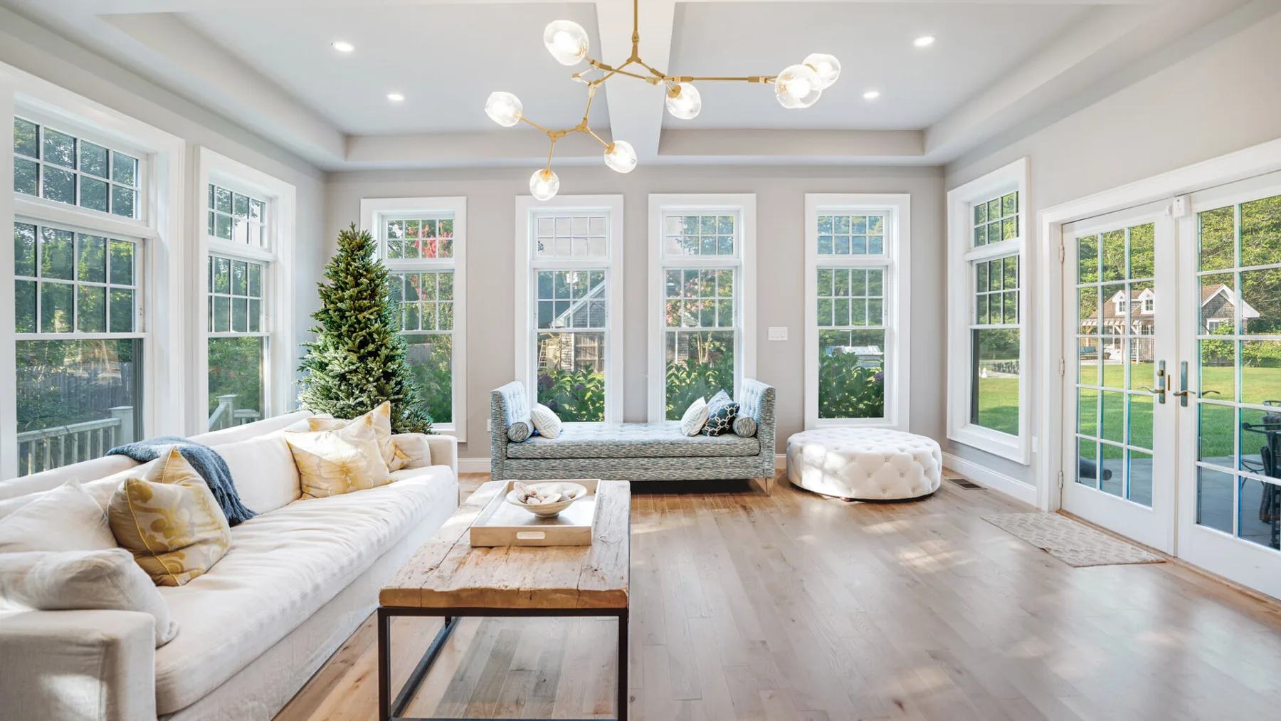 A bright living room with white seating and large windows.