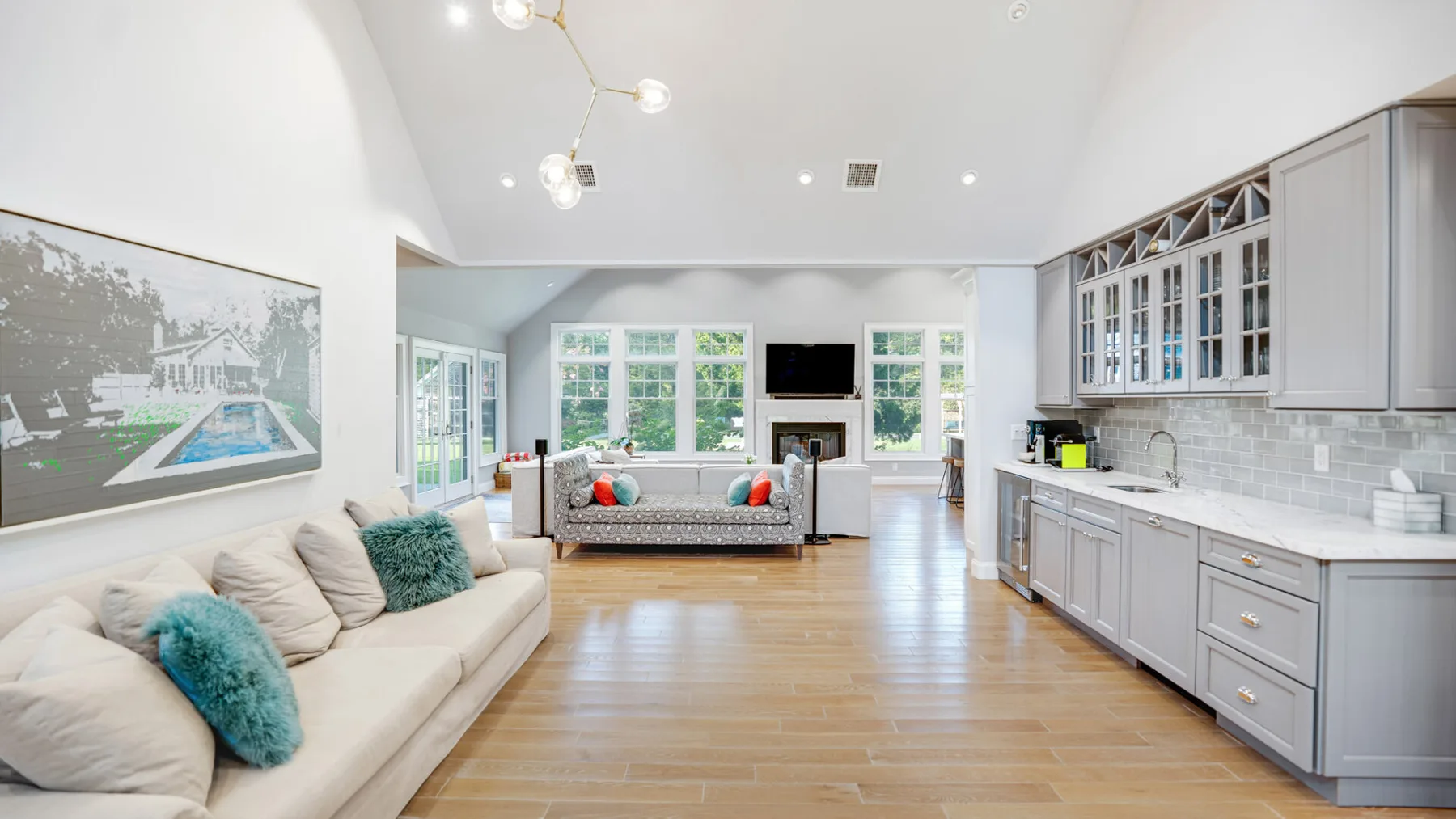 A bright open-plan living room and kitchen with sofas and a long counter.