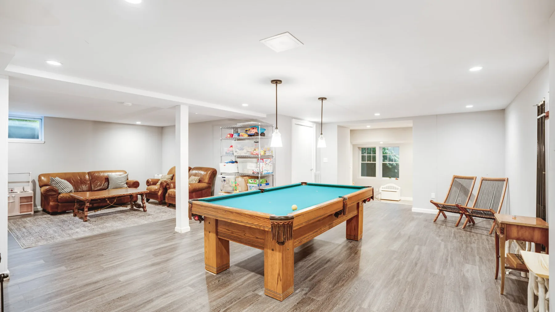 A recreation room with a pool table and seating.