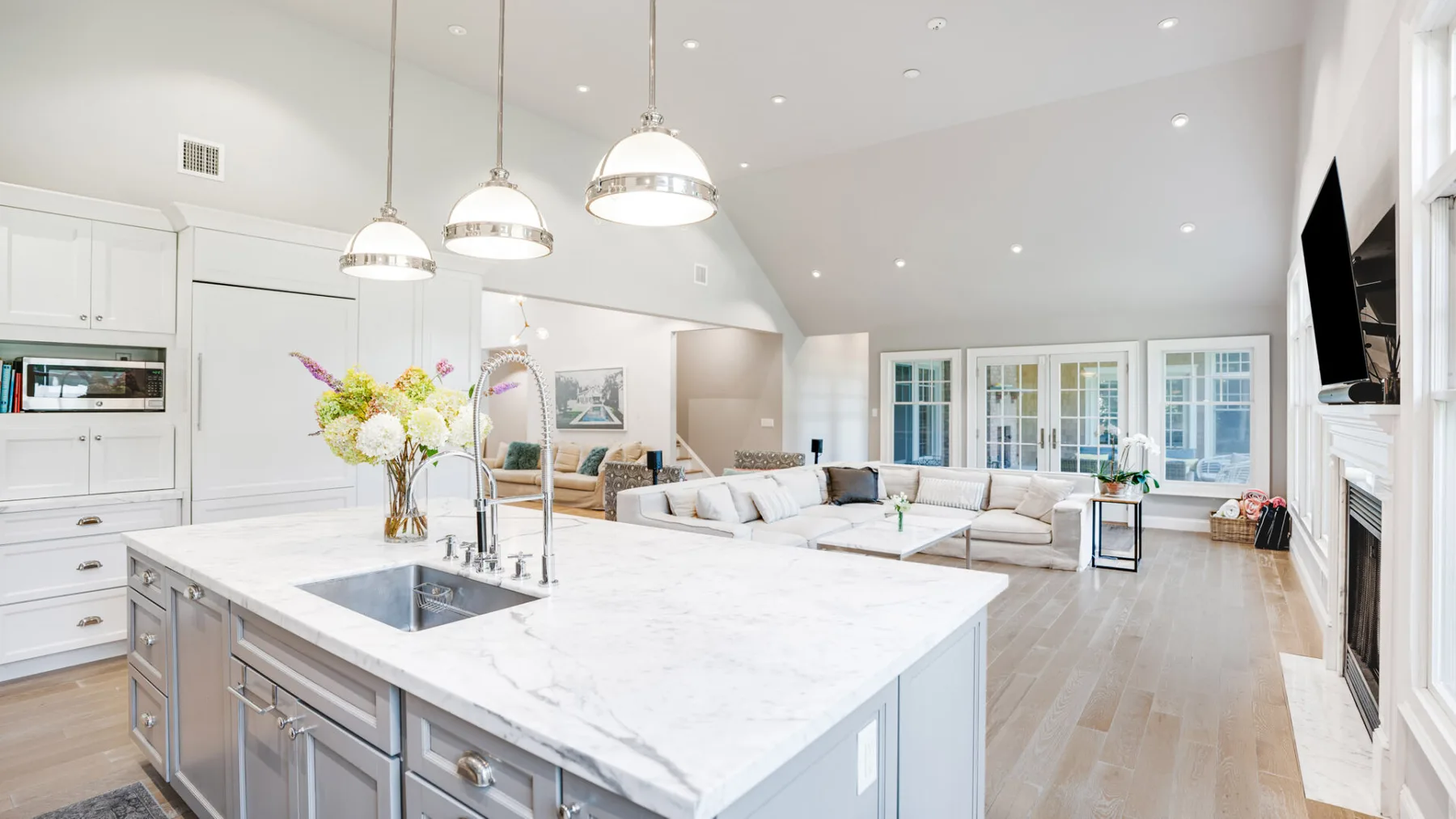 A bright open-plan kitchen and living area with a large island and sectional seating.
