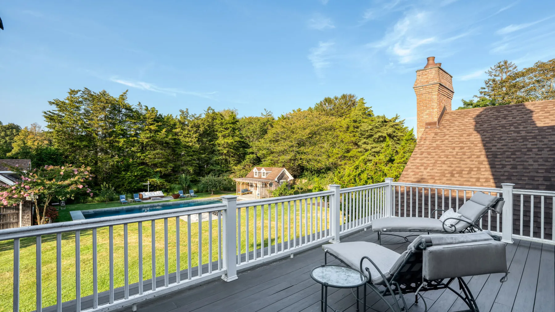 A raised outdoor deck overlooks a green lawn and leafy trees.