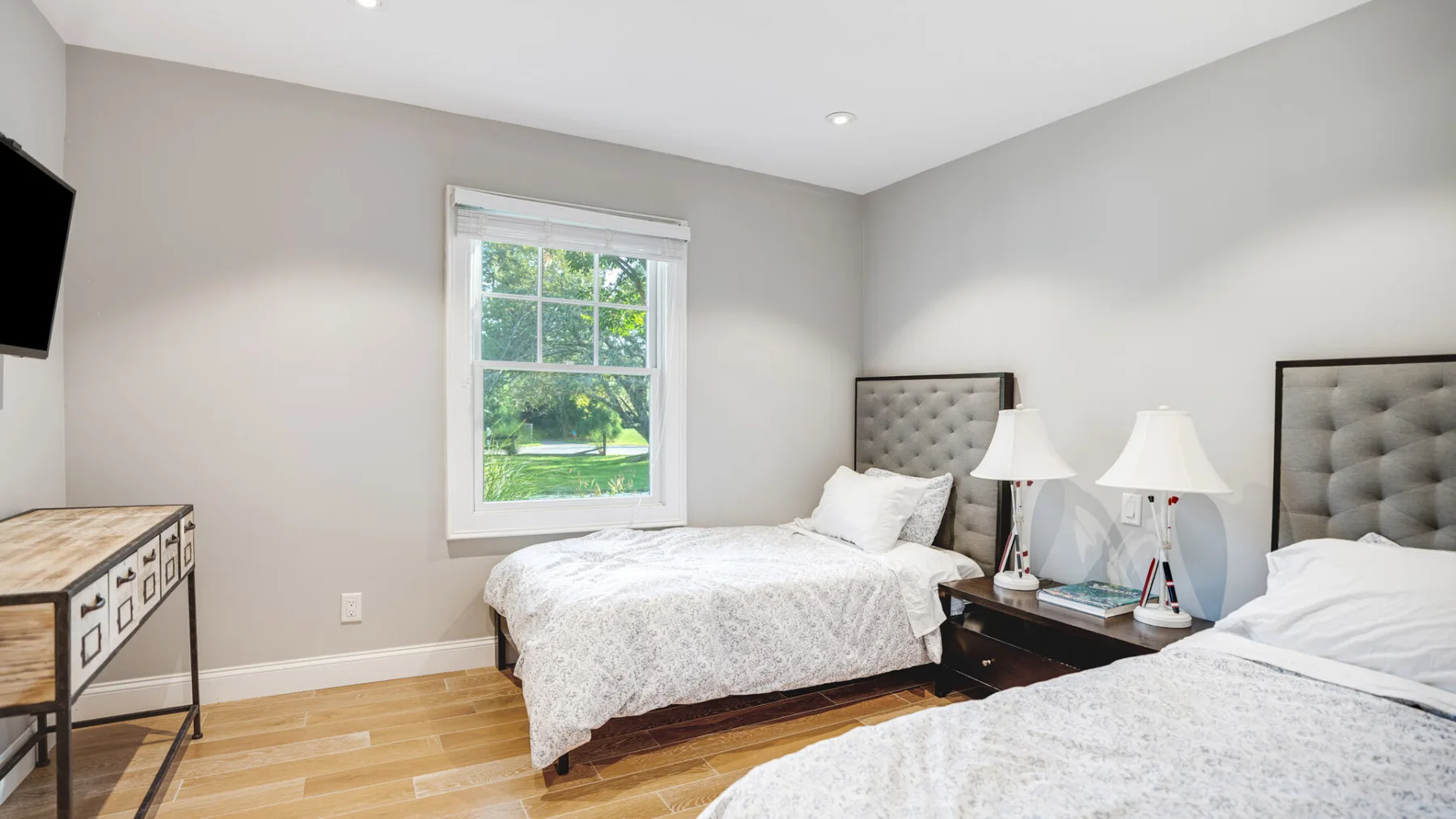 A bright bedroom with two beds beside a window.