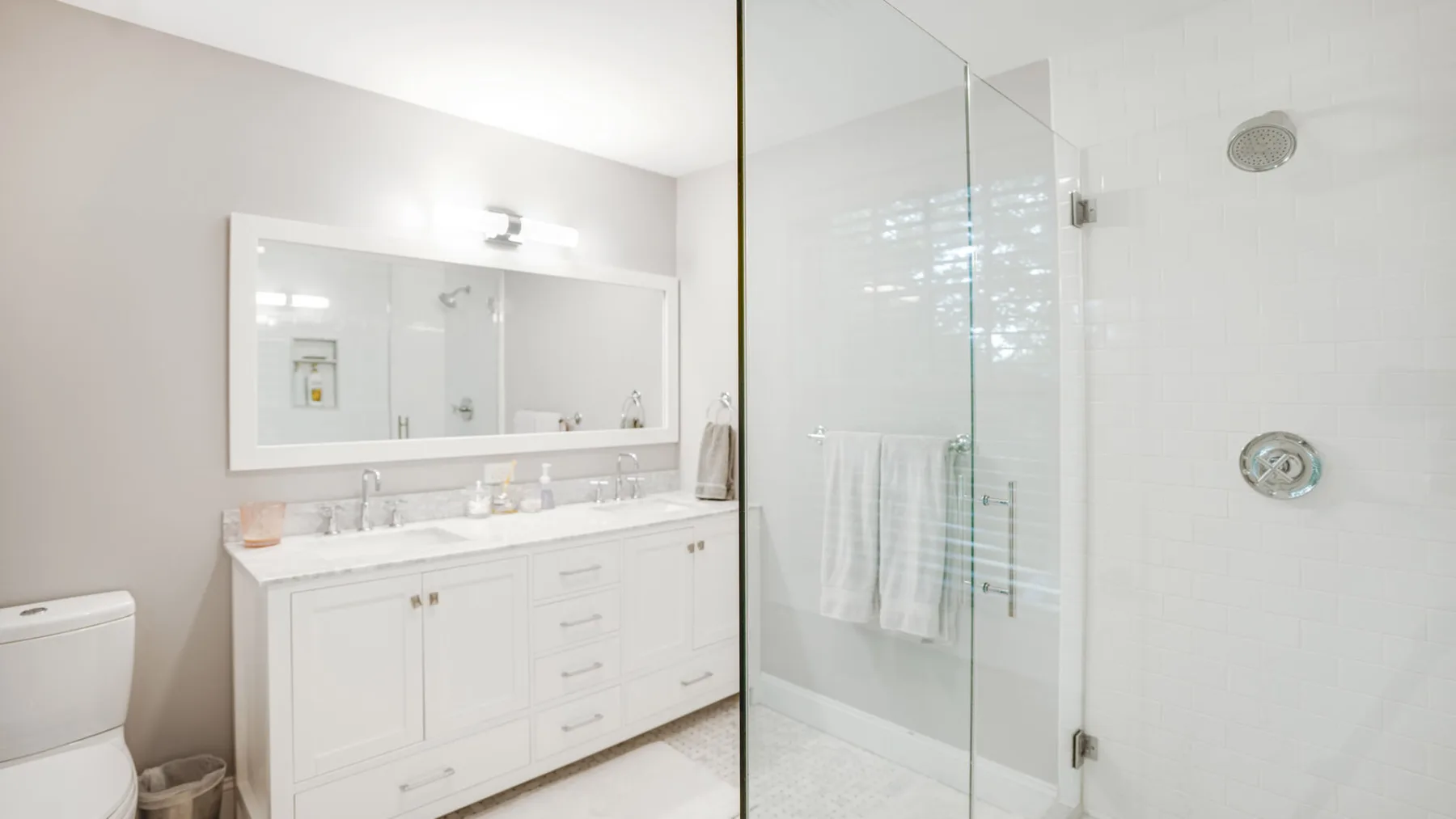 A bright bathroom with a long vanity and a glass shower.
