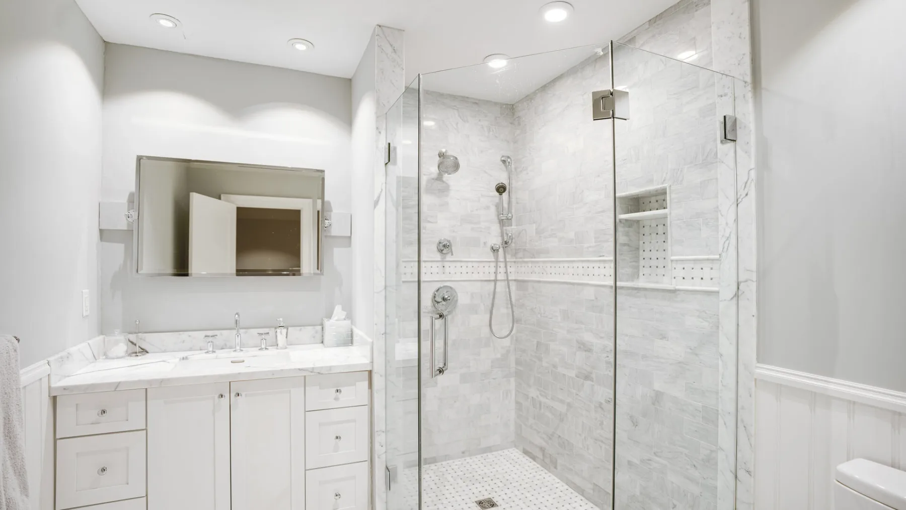 A bright bathroom with a vanity and a glass-enclosed shower.