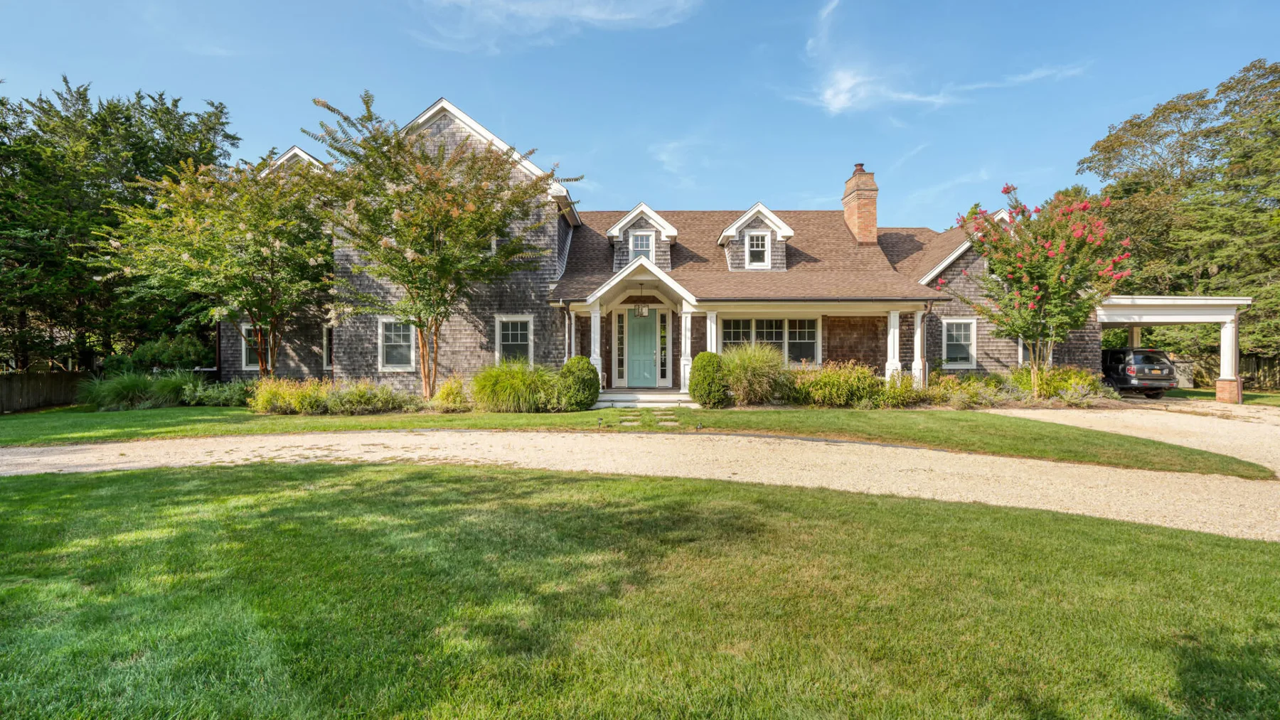 A large house with a lawn and driveway in front.