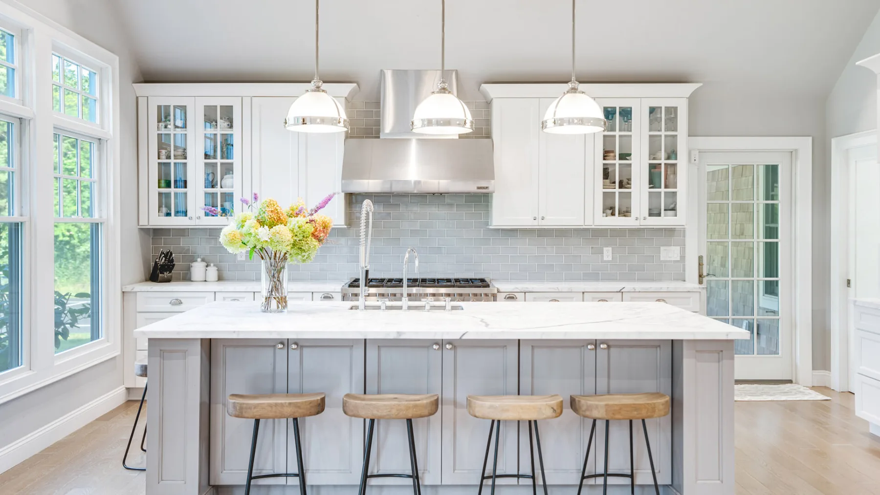 A bright kitchen with a large island and pendant lights.