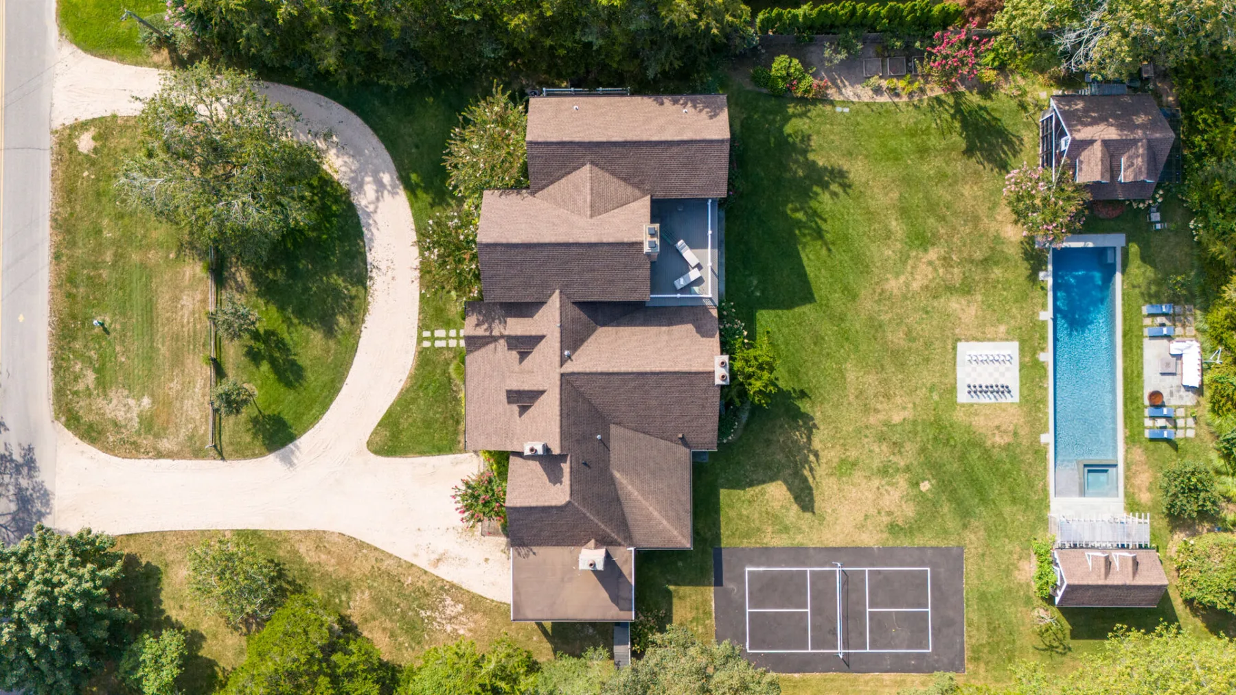 An aerial view shows a house, lawn, swimming pool, and sports court.