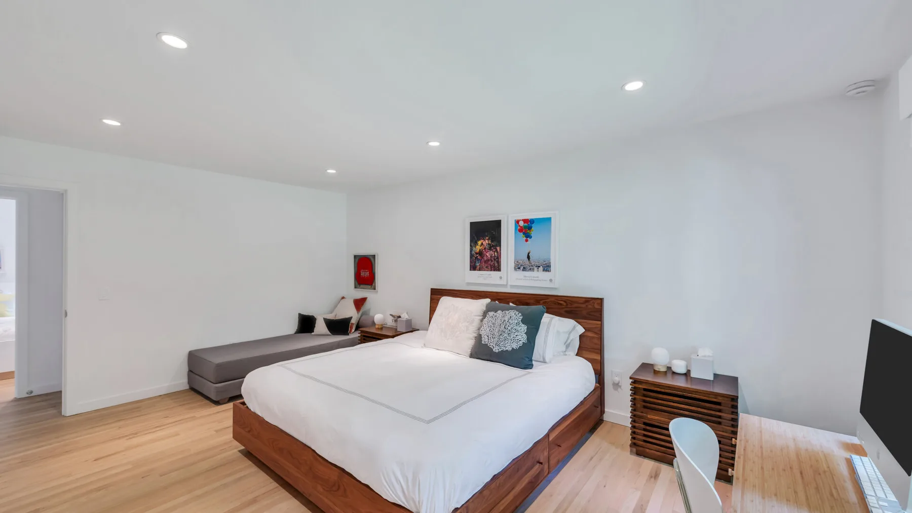 A bright bedroom with a large bed and a gray seating area.