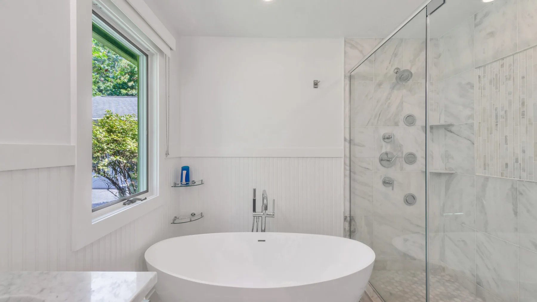 A bright bathroom with a freestanding bathtub beside a glass shower.
