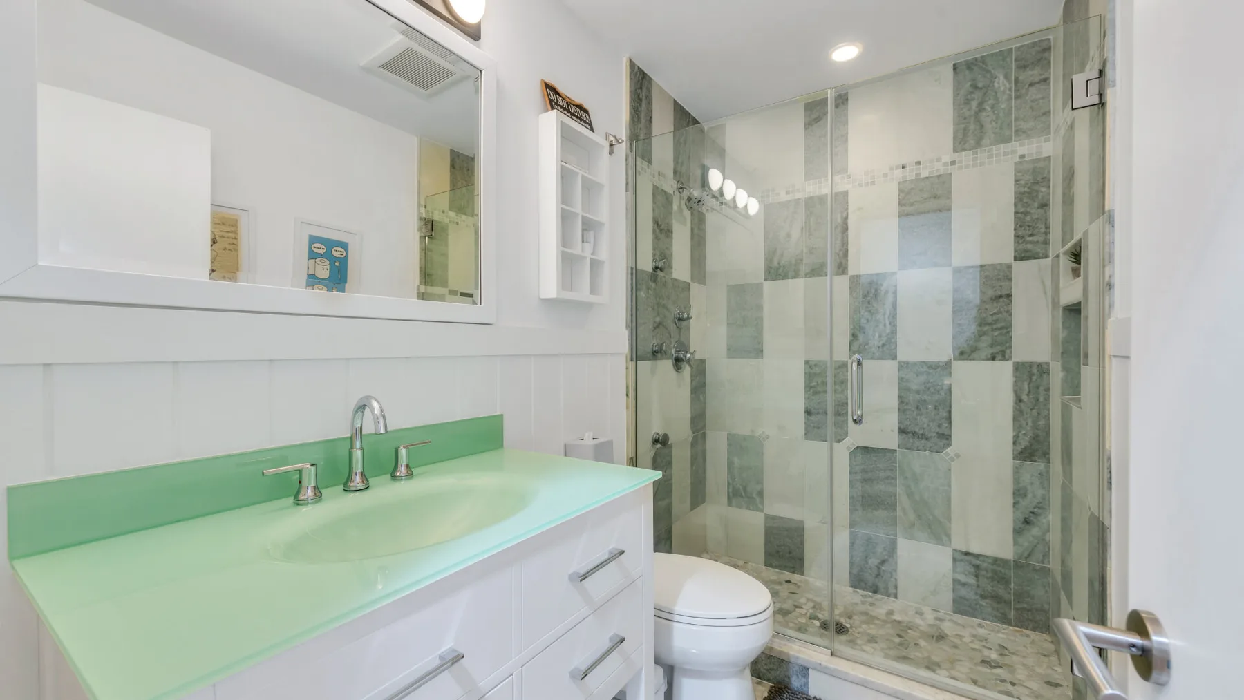 A bathroom with a green vanity and a tiled shower.