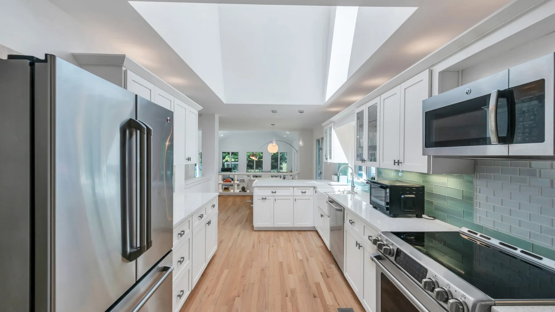 A bright kitchen with white cabinets, stainless steel appliances, and a central island.