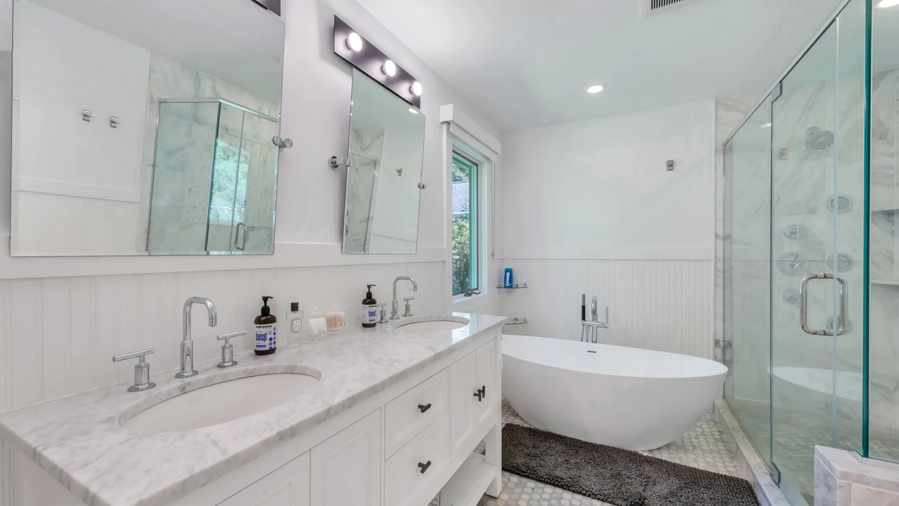 A bright bathroom with a freestanding bathtub beside a glass shower.