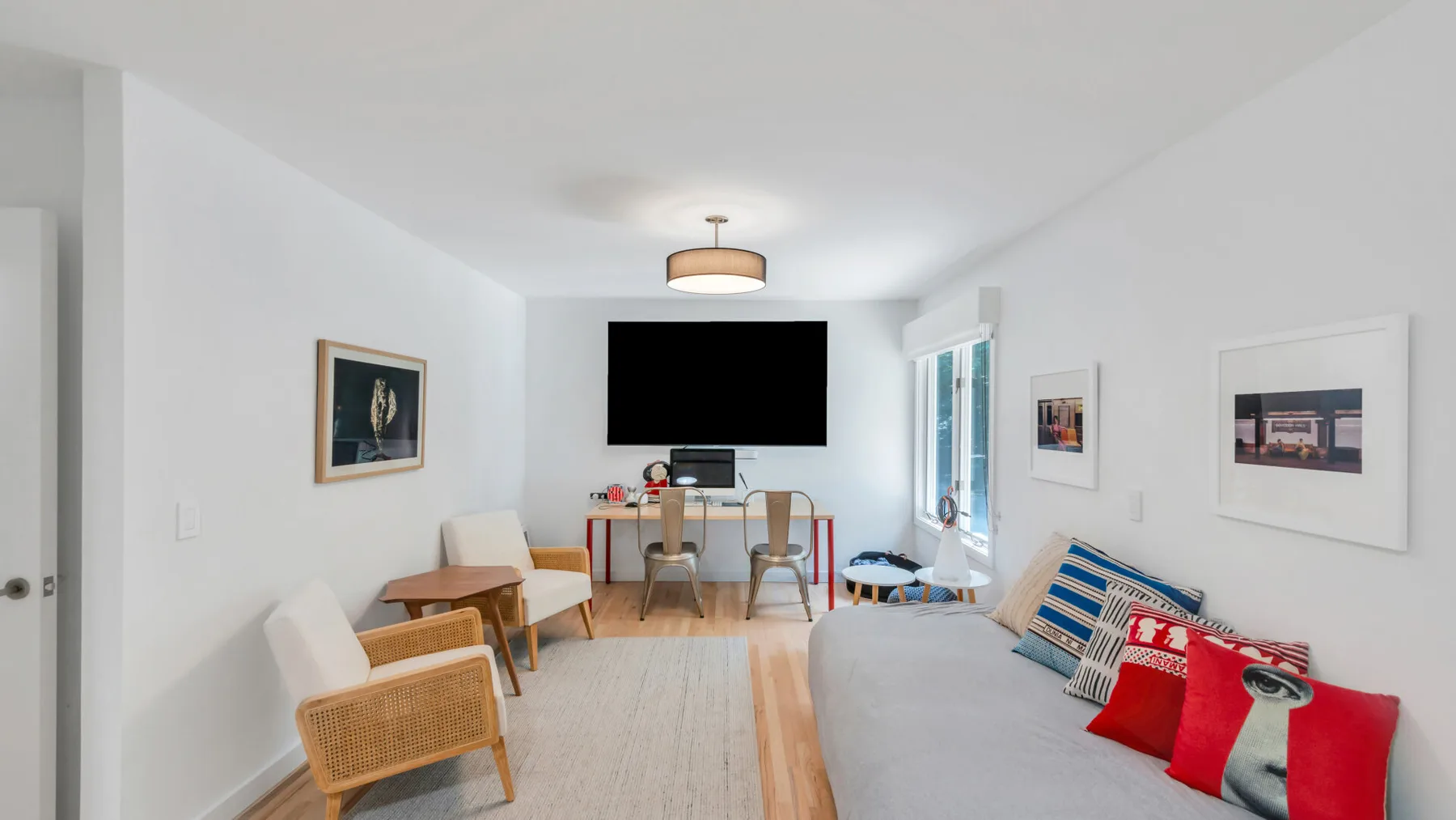 A bright living room has a sofa, dining table, and television.