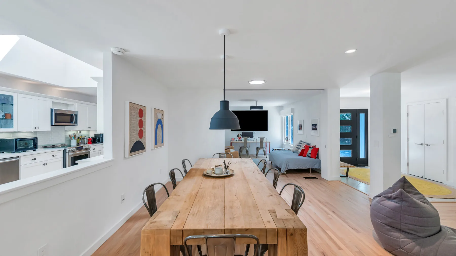An open-plan living and dining area with a long wooden table and seating.
