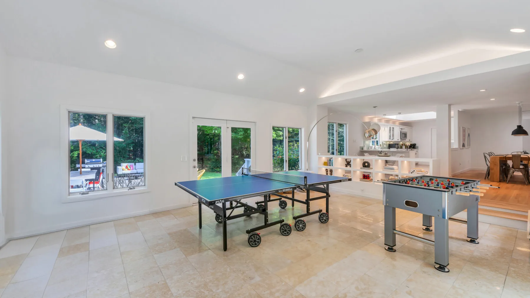 A bright game room with a table tennis table and foosball table.