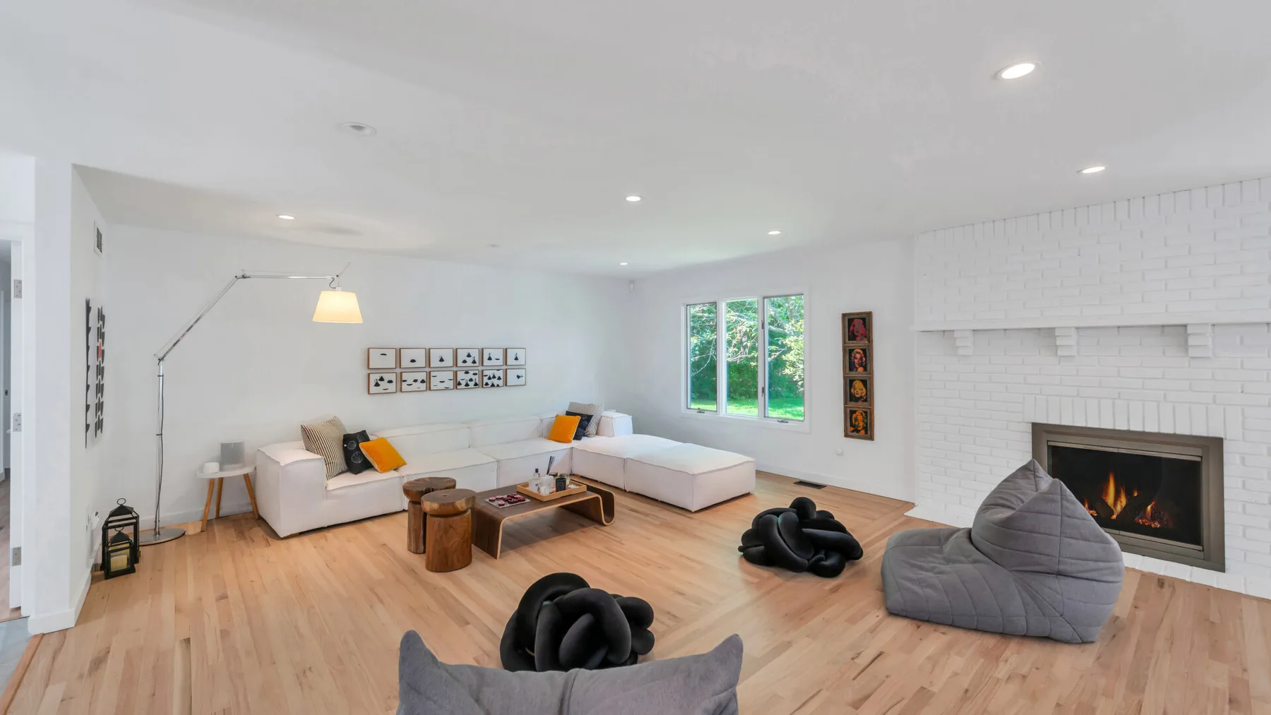 A bright living room with seating, a fireplace, and large windows.