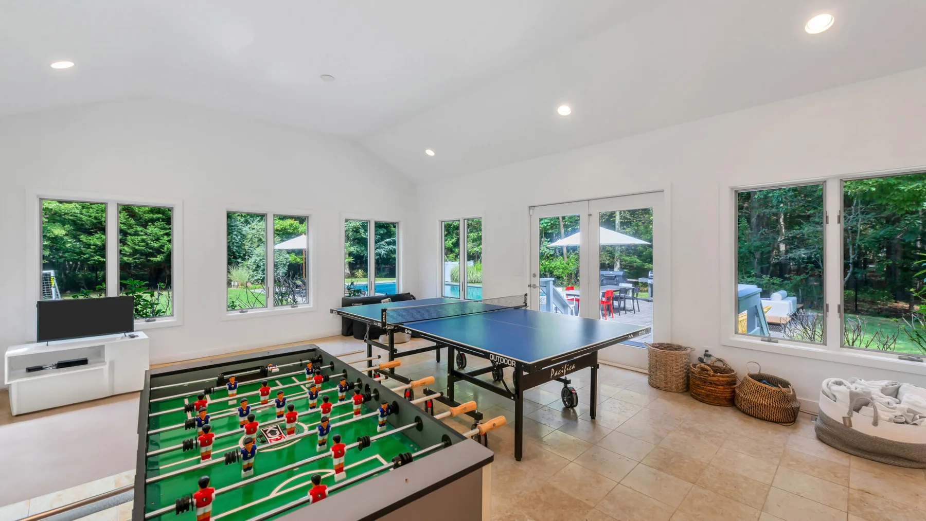 A bright game room features a foosball table beside large windows.