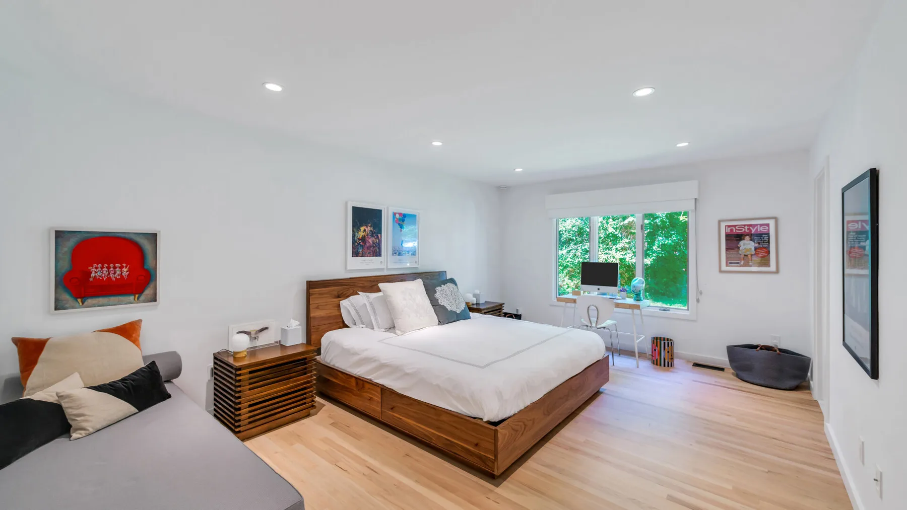 A bright bedroom has a large bed and a window overlooking greenery.