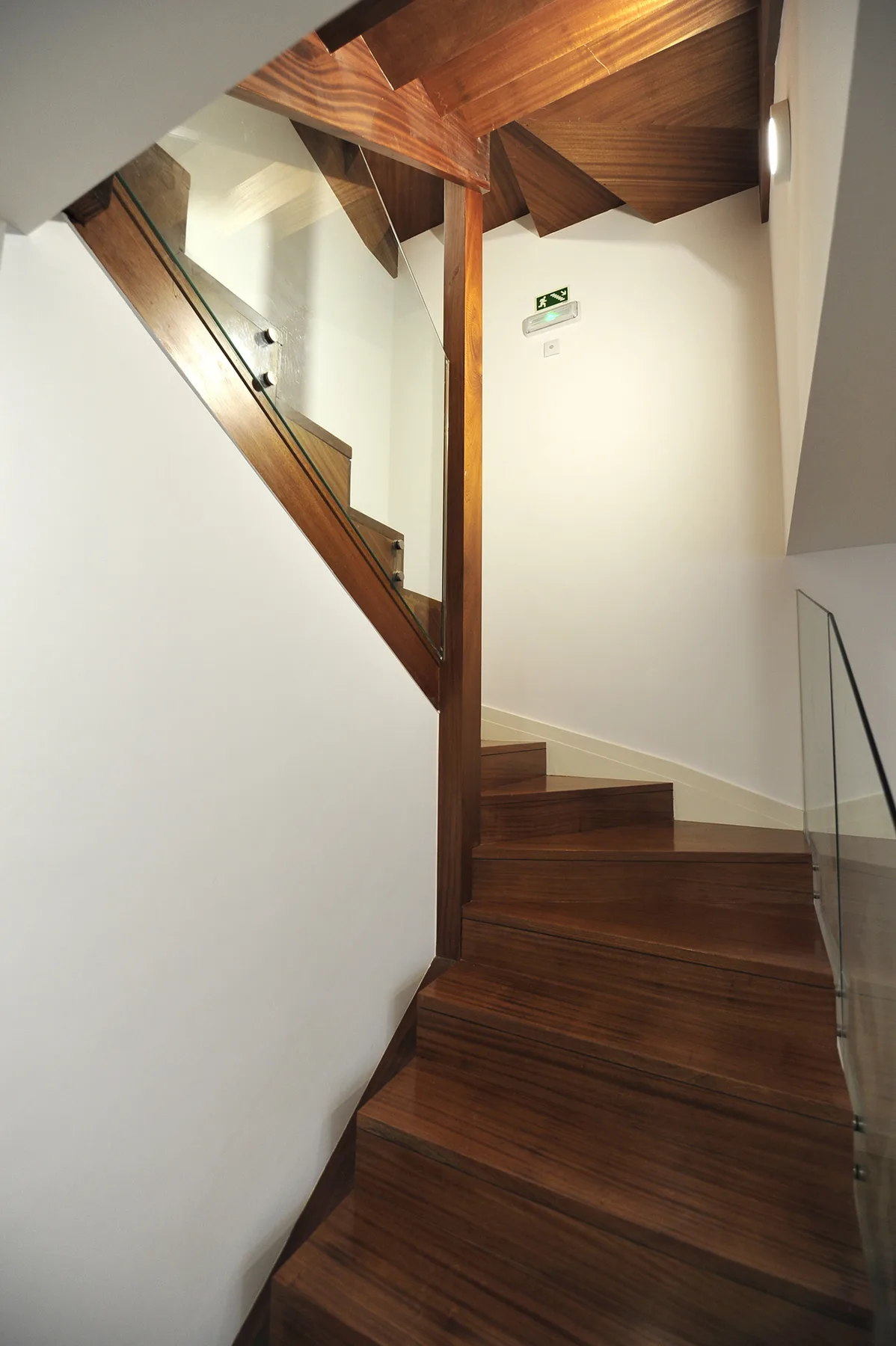 An interior staircase with dark wooden steps and a glass railing.