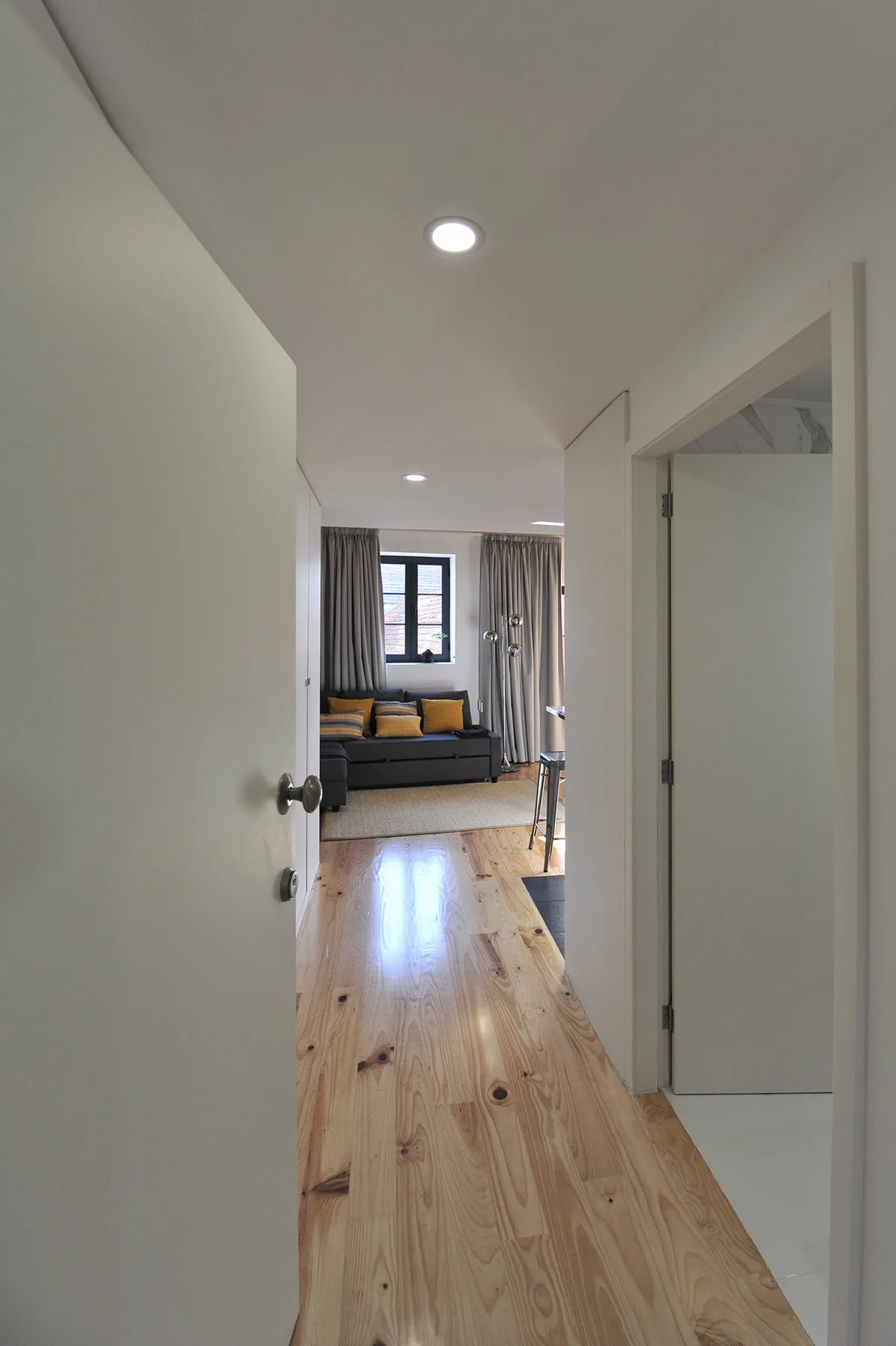A hallway opens toward a living area with a sofa and a window.