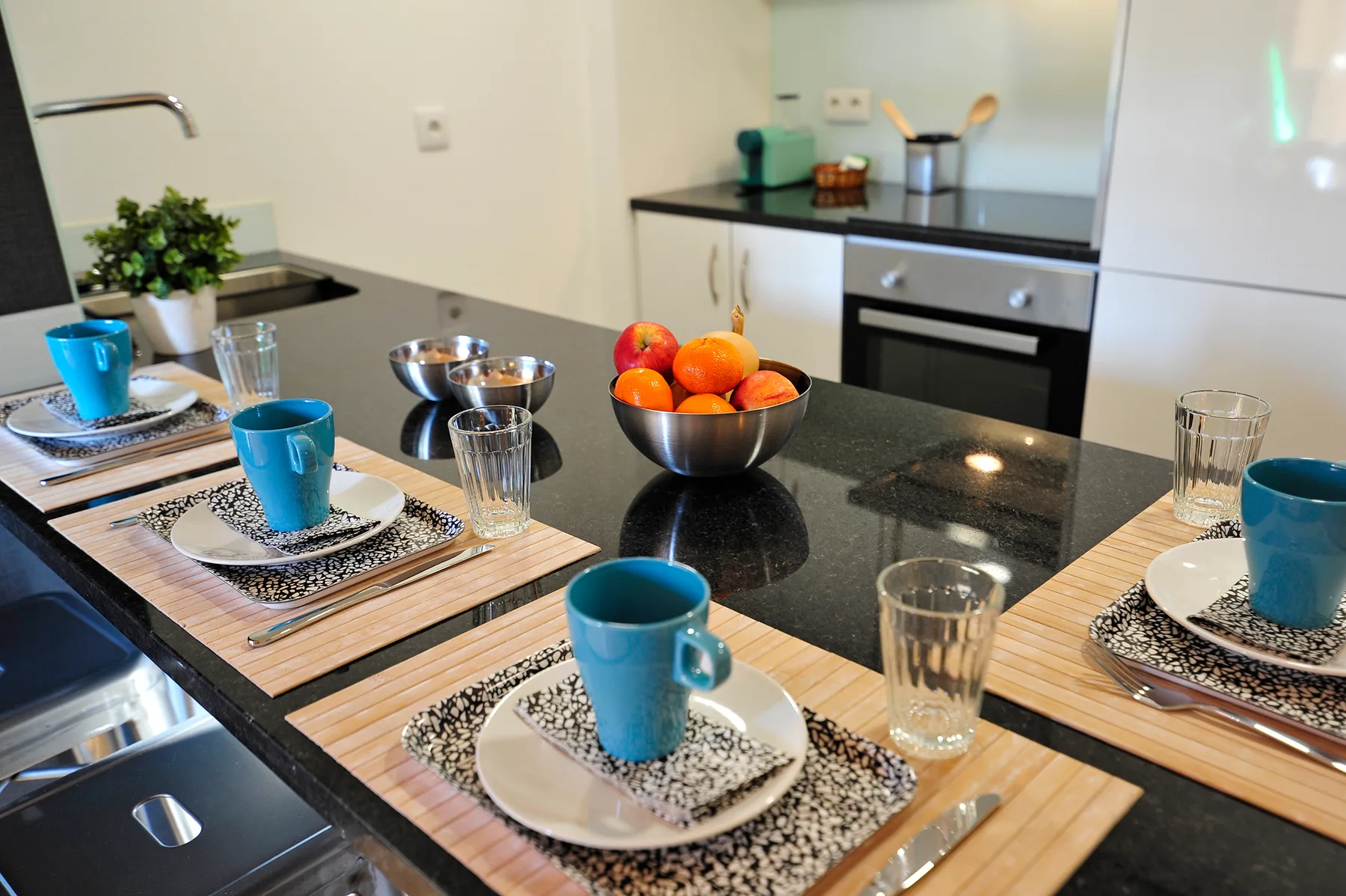 A kitchen dining area with place settings arranged on a dark countertop.