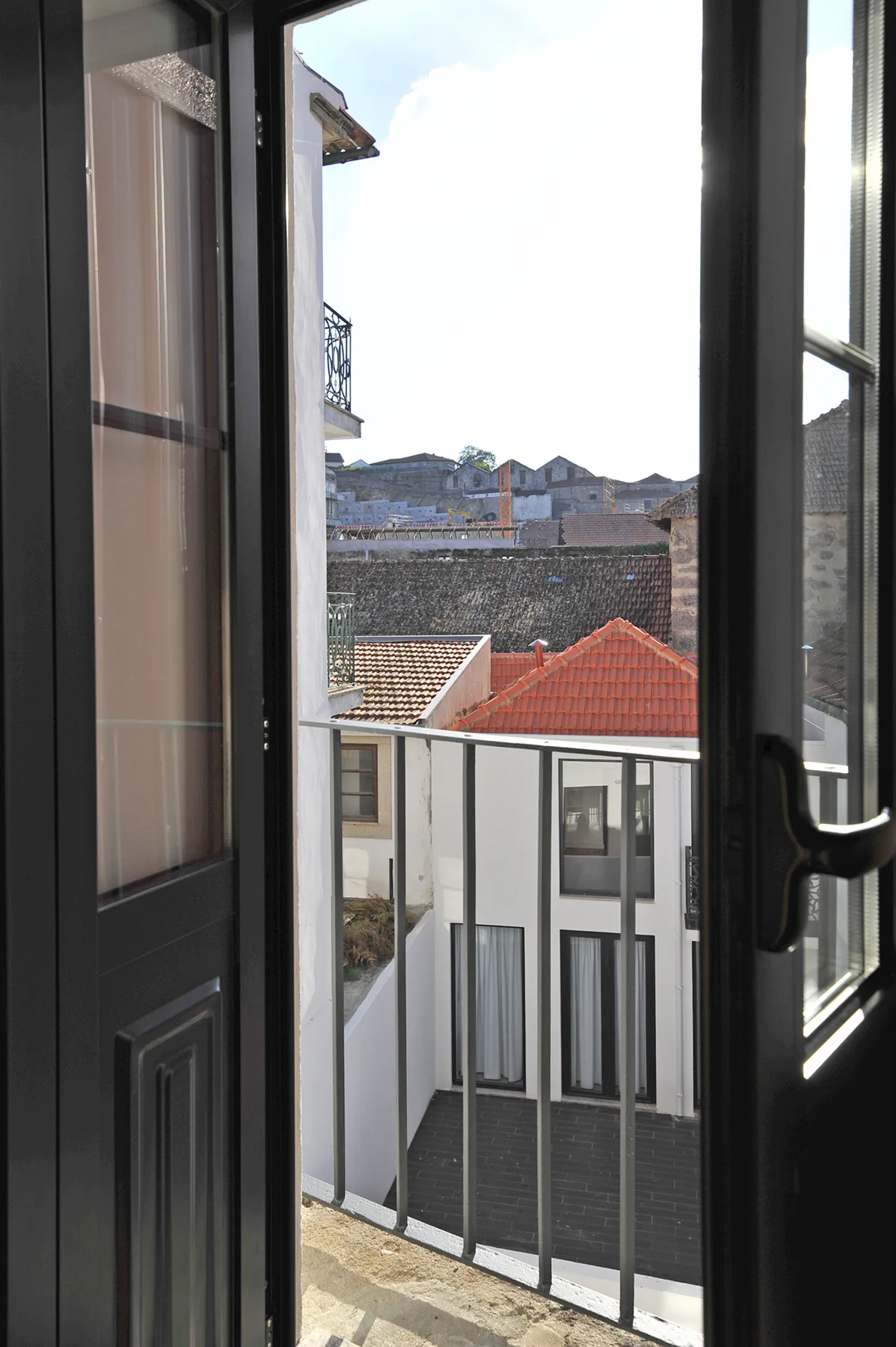 An open window overlooks neighboring rooftops and a balcony railing.