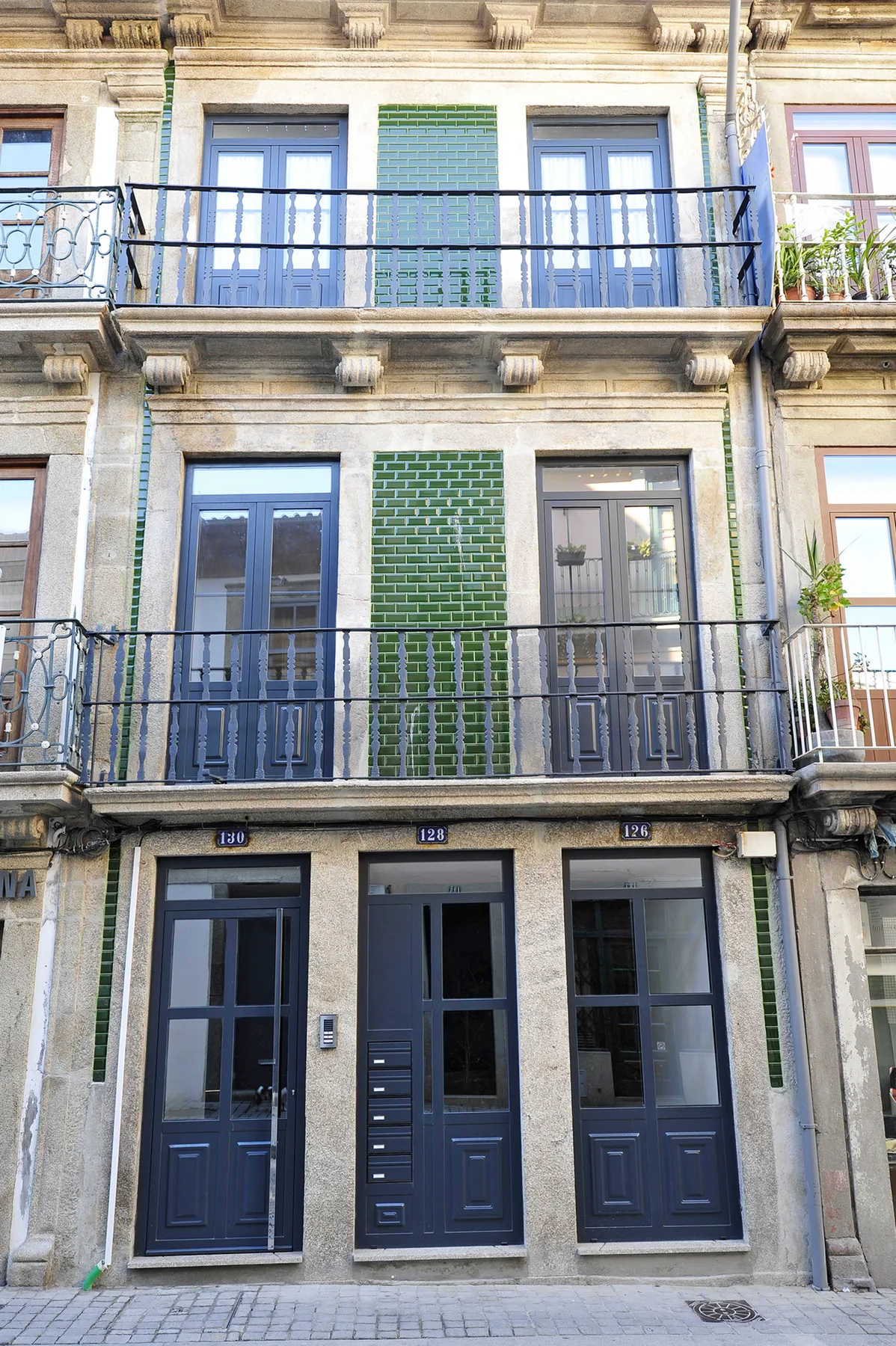 A multi-story building facade with balconies, windows, and dark blue doors.