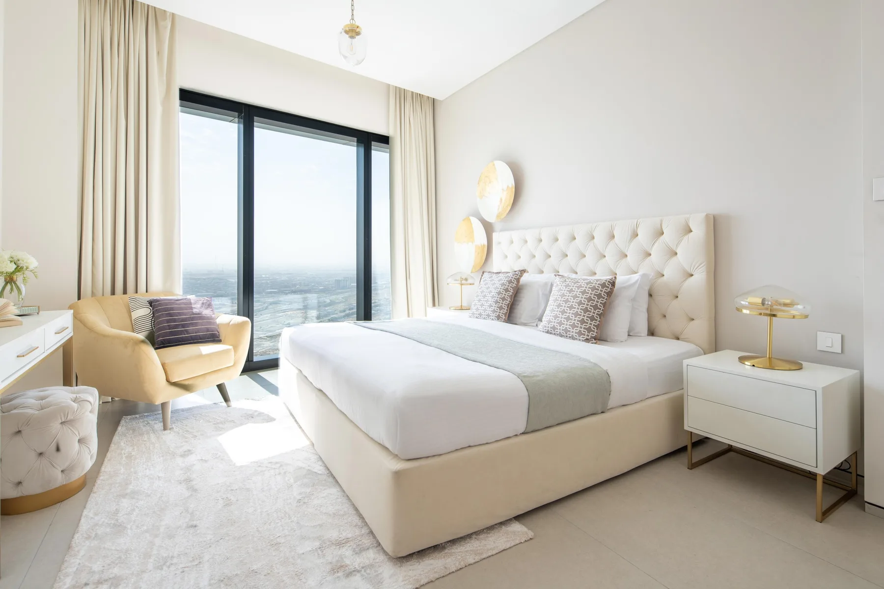 Un dormitorio luminoso con una cama arreglada y una ventana grande.