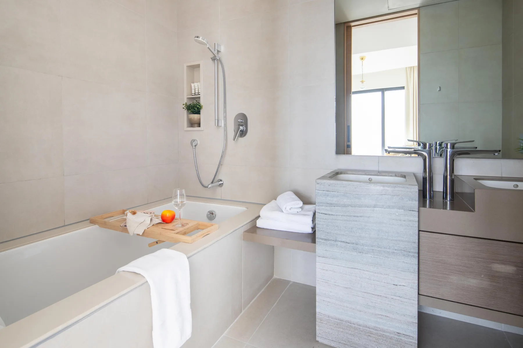 Un baño luminoso con bañera, ducha y lavabo.