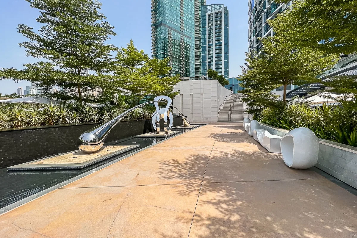 Una terraza exterior pavimentada con un canal de agua estrecho y árboles alrededor.