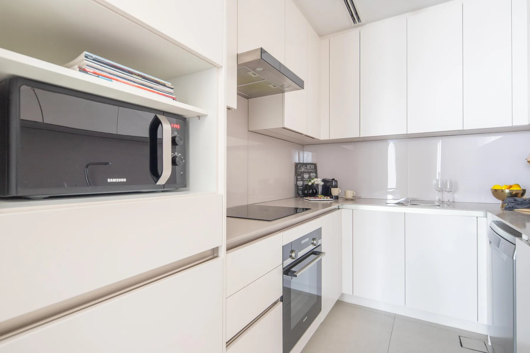 Una cocina luminosa con gabinetes blancos, microondas empotrado y horno.