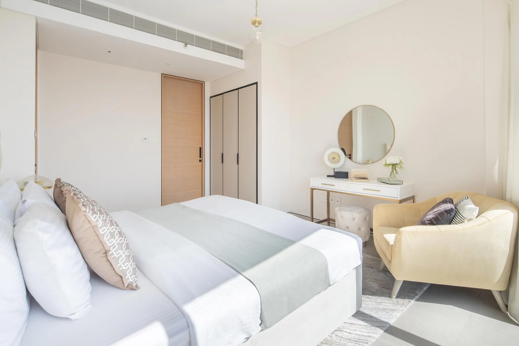 Un dormitorio luminoso con una cama, un escritorio pequeño y un sillón.