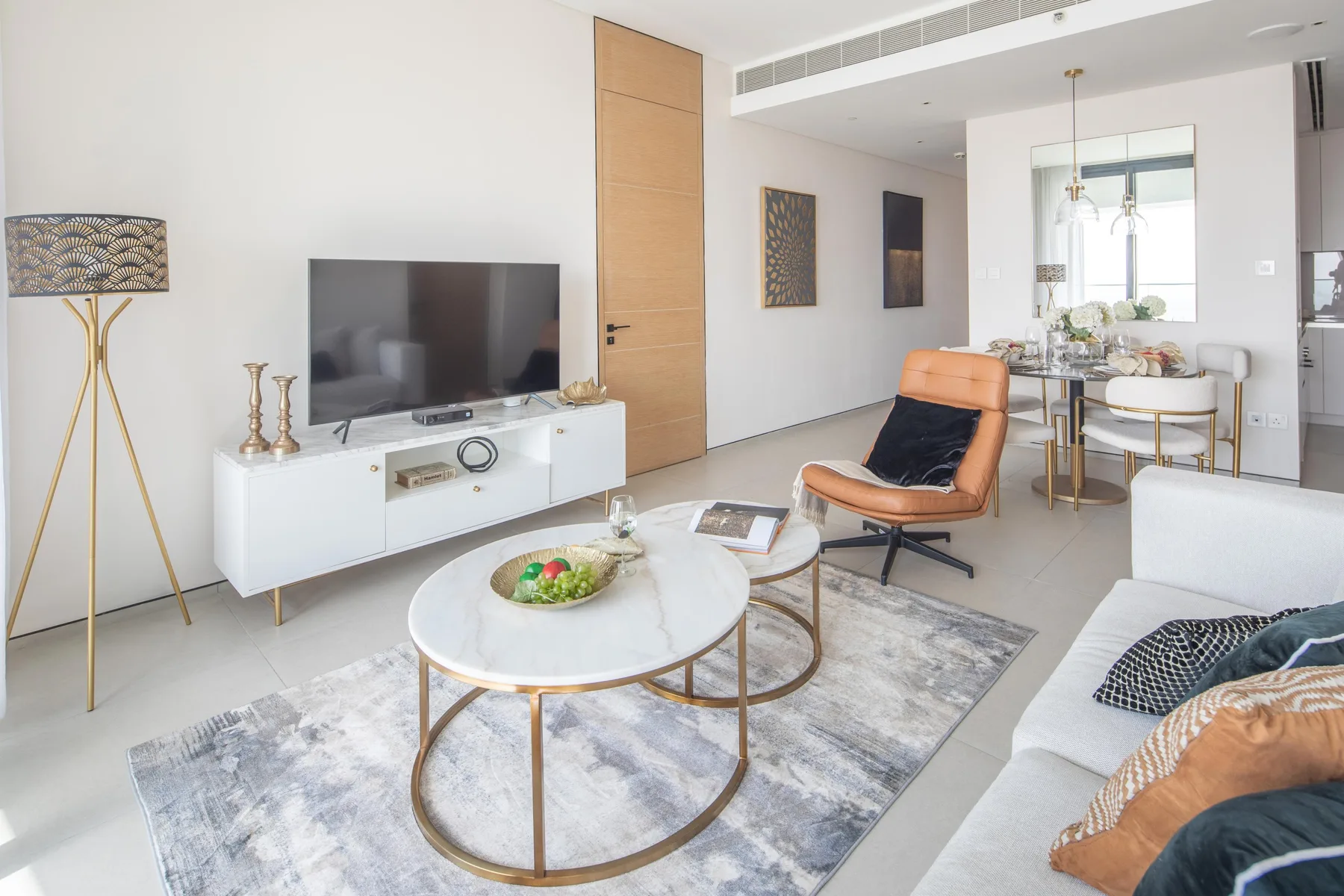 A bright living room with a television, seating, and a round coffee table.