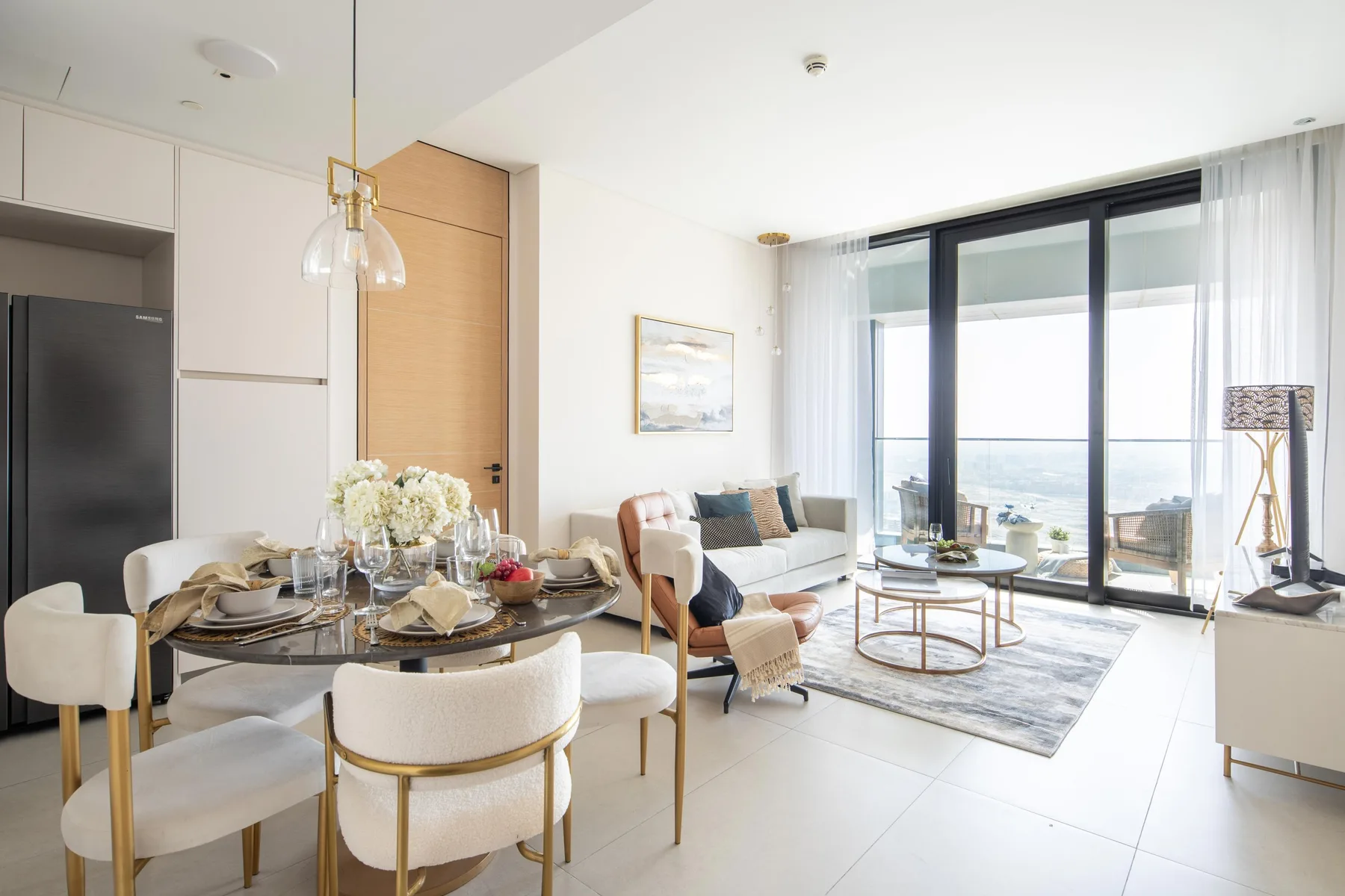 An open-plan living and dining area with seating beside large windows overlooking the water.