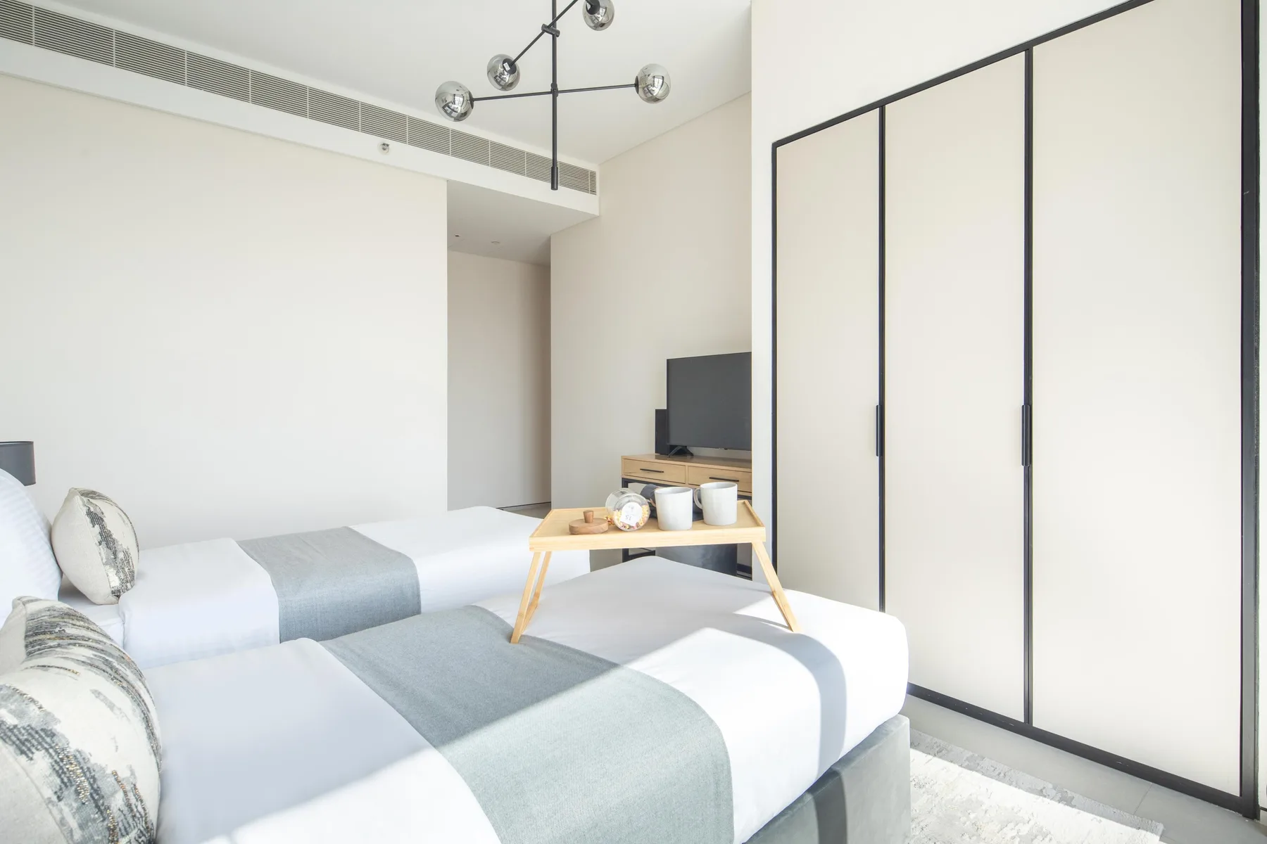 Un dormitorio luminoso con dos camas y un televisor sobre una mesa baja.