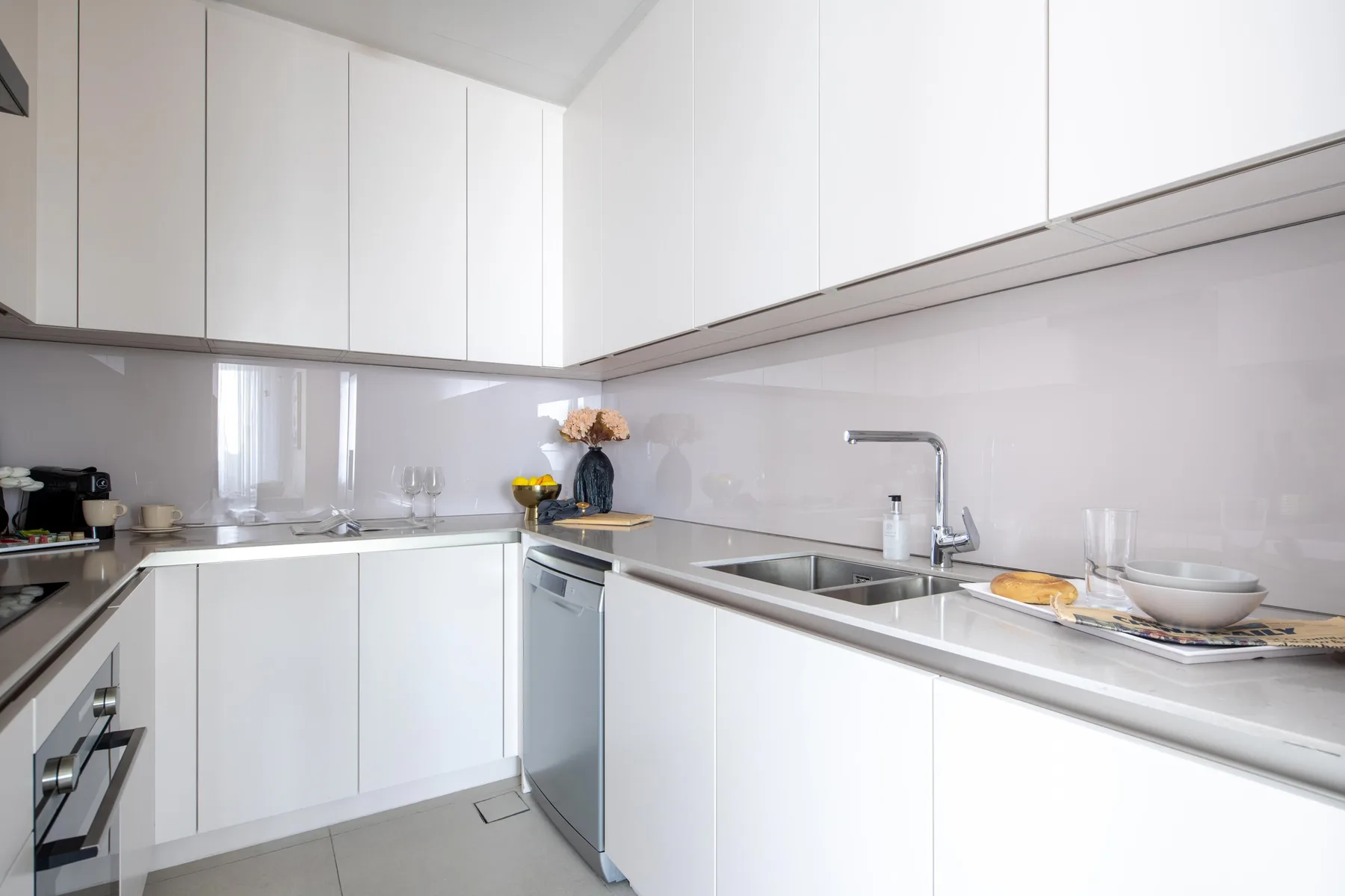 Una cocina luminosa con gabinetes blancos, encimeras y un fregadero.