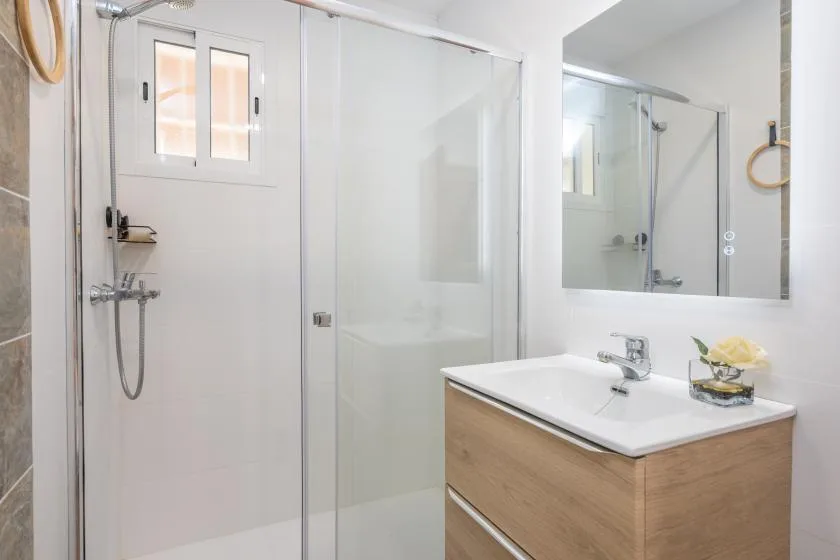 A bright bathroom with a glass shower and a wood-tone vanity.