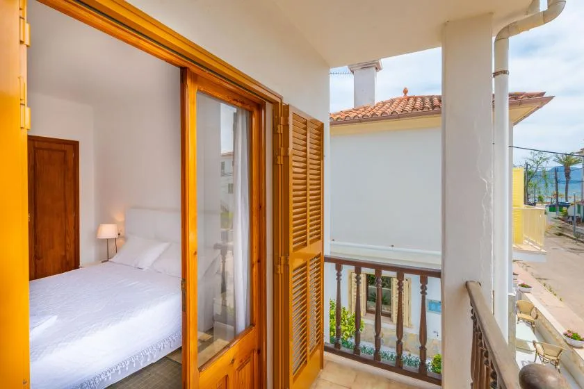 A bedroom opens onto a small balcony with a wooden railing.
