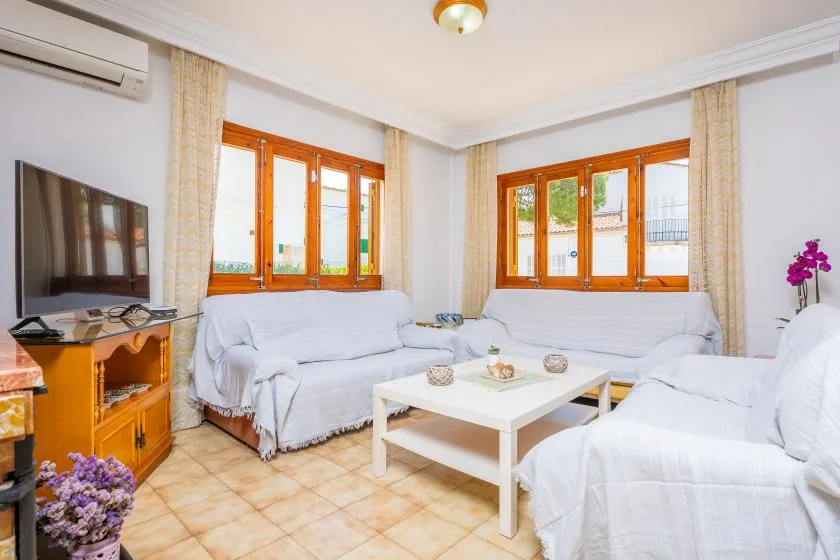 A bright living room with seating around a white coffee table and windows.