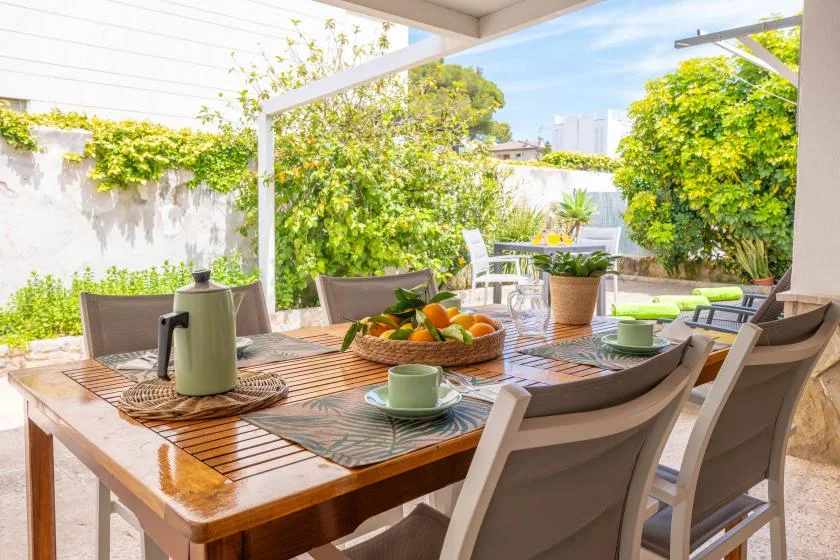 An outdoor dining area with a wooden table set beneath a covered patio.