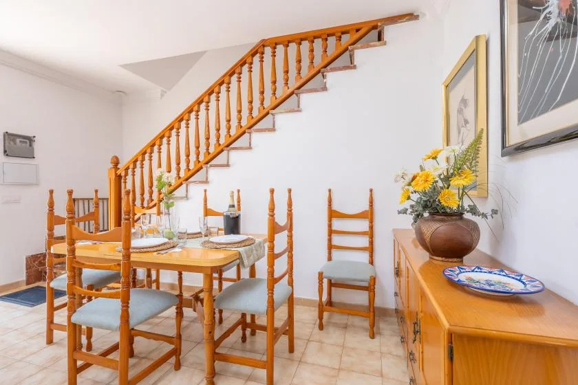 A dining area with a wooden table and chairs beneath a staircase.