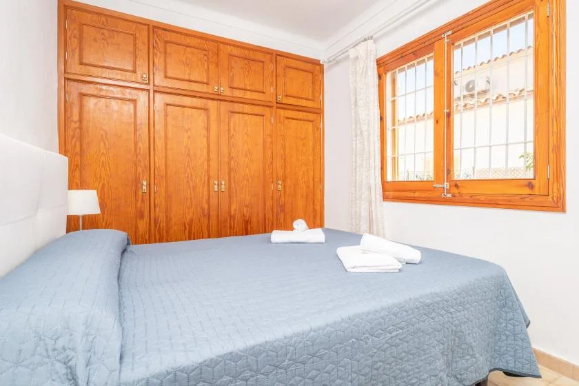 A bedroom with a bed, wooden wardrobe, and a window.