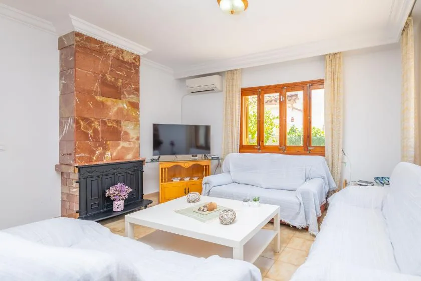 A bright living room with seating, a coffee table, and a television.