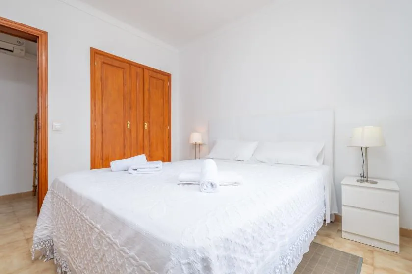 A bright bedroom with a large bed and wooden doors.