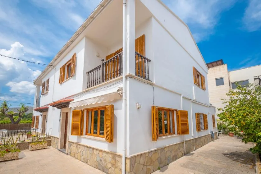 A white two-story house with wooden shutters and a small balcony.