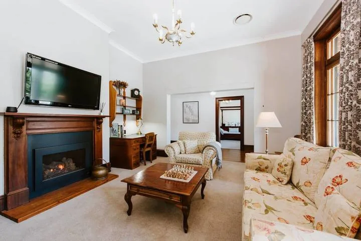 Sala de estar con chimenea, televisor y asientos florales.