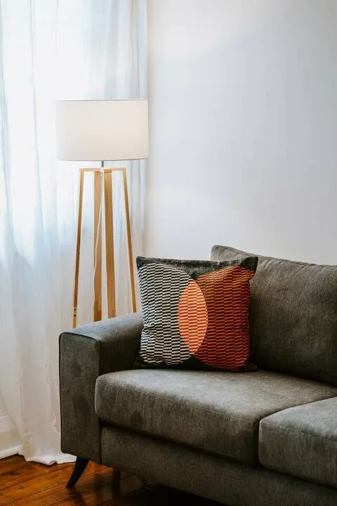 Una zona de estar con un sofá gris y una lámpara de pie.
